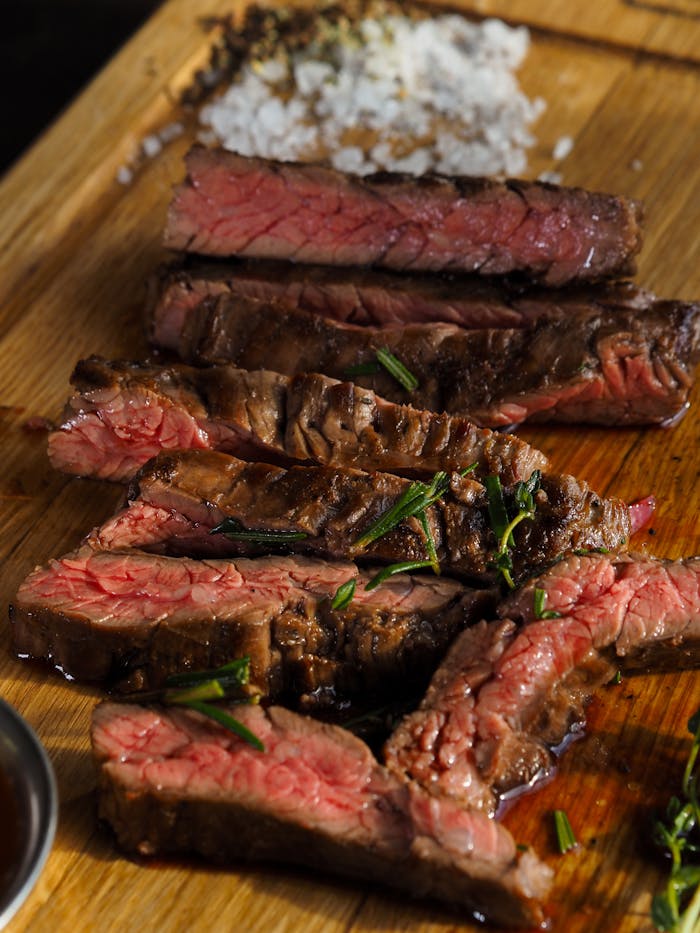 Mastering the First Impression: Your intriguing post title goes here Close-up of sliced grilled steak with seasoning on a wooden board, highlighting texture and juiciness.